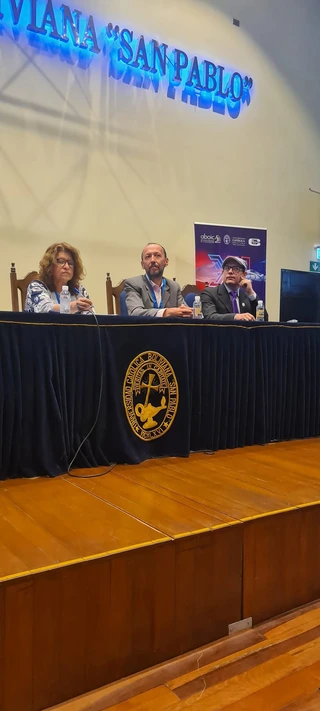 Enrique Revollo sentado junto a otros dos panelistas en el encuentro de ABOIC en la Universidad Católica Boliviana.